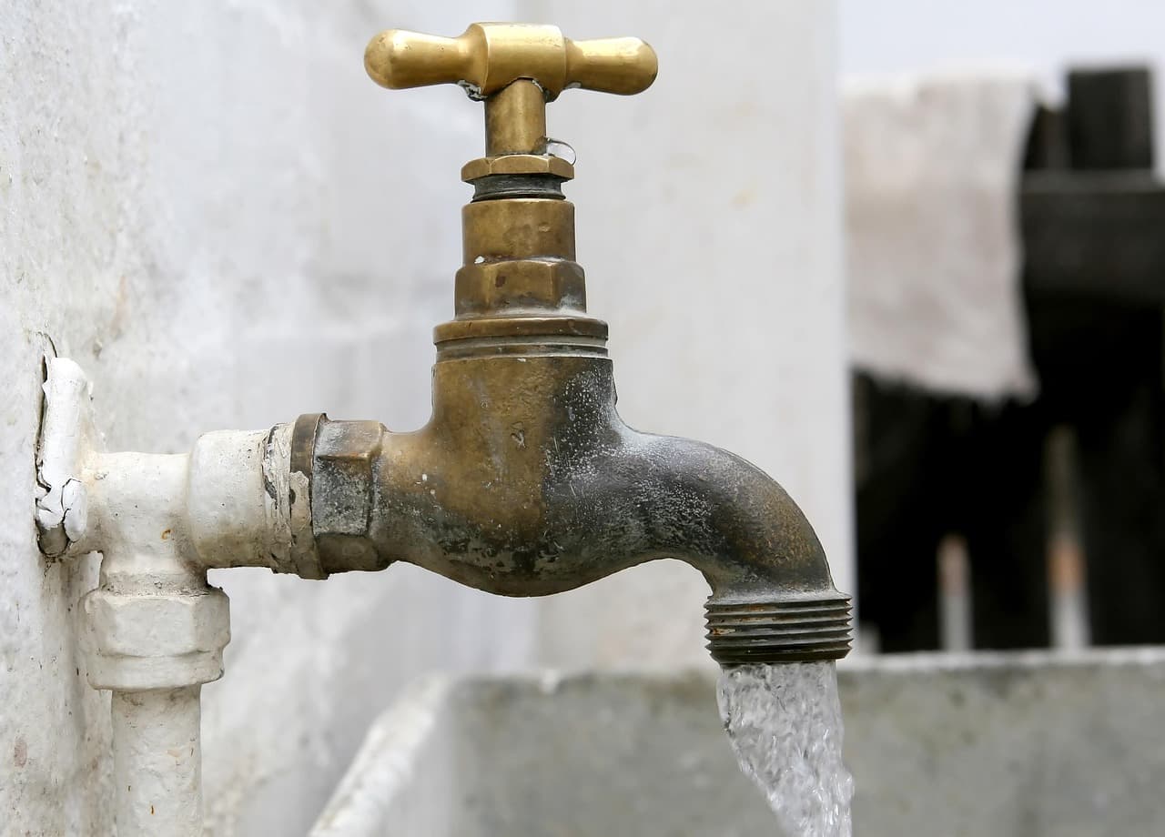 An old brass tap running into a stone basin