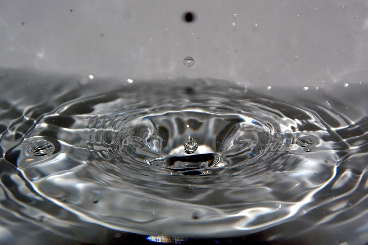A drop of water landing in a still pool, close up