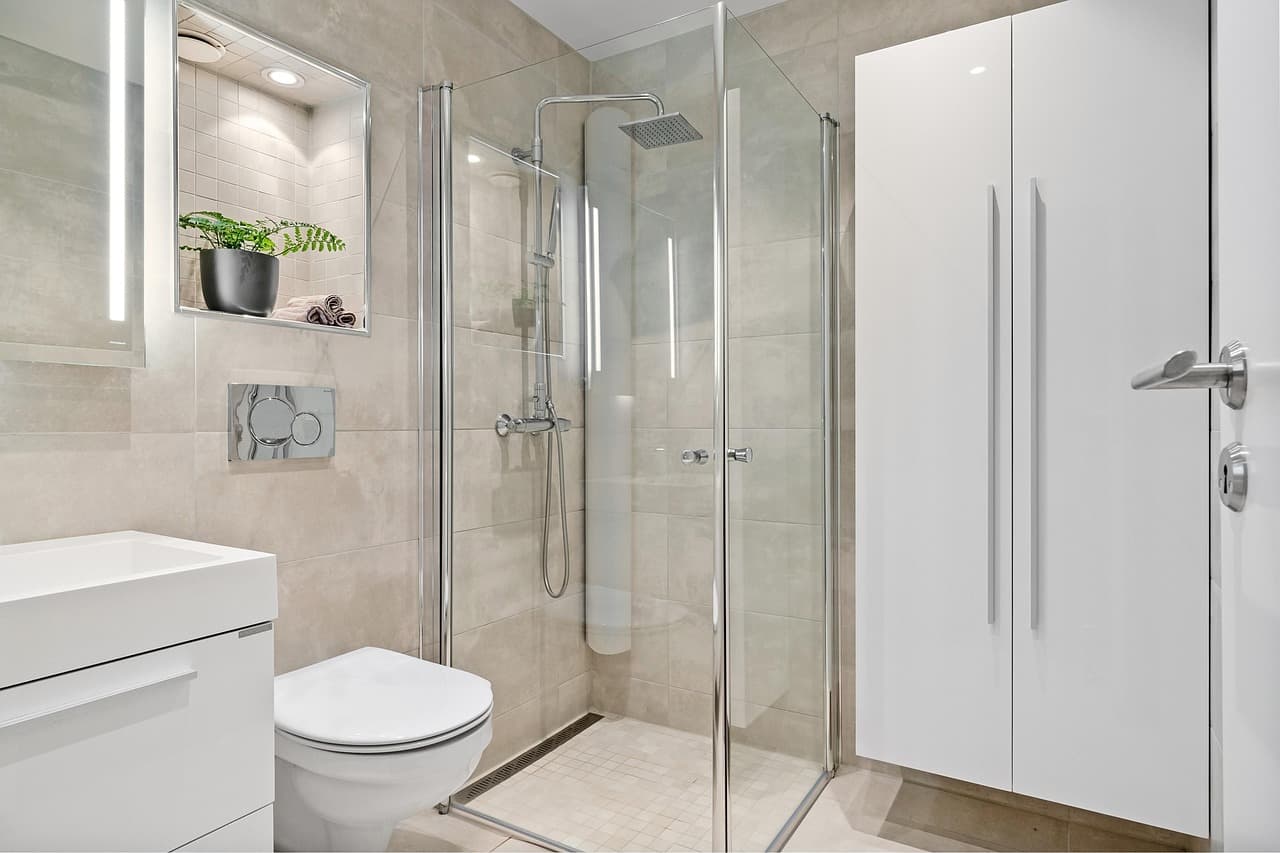 A finished bathroom with a walk-in glass shower, wall-hung toilet and basin